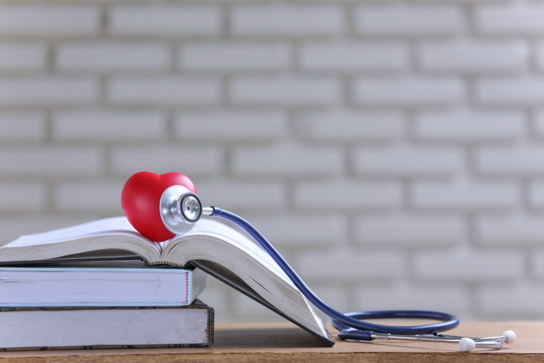 Livros de estudo empilhados com um estetoscópio e um coração vermelho